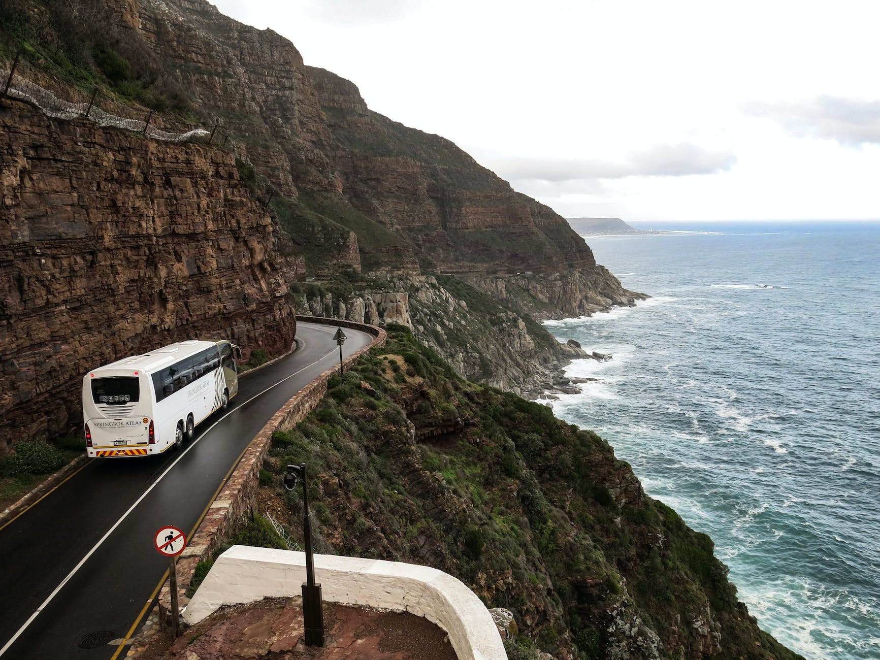 white bus on road near cliff